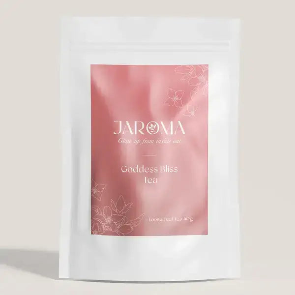 A vibrant front packaging of Jaroma Goddess Bliss Tea, featuring a soft pink background adorned with delicate floral illustrations. The label prominently displays the product name 'Goddess Bliss Tea' in elegant typography, with a note indicating the tea is loose-leaf in a 40g pouch.